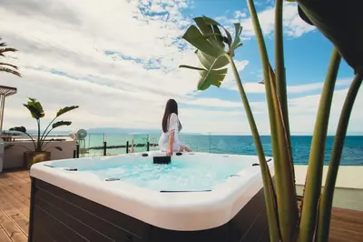 a woman standing in a bath tub with the ocean in the background at Villa Vriko in Agia Marina Nea Kydonias