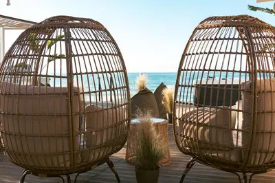 two bird cages sitting on a deck with the beach at Villa Vriko in Agia Marina Nea Kydonias