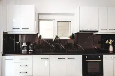a kitchen with white cabinets and black counter tops at Villa Vriko in Agia Marina Nea Kydonias