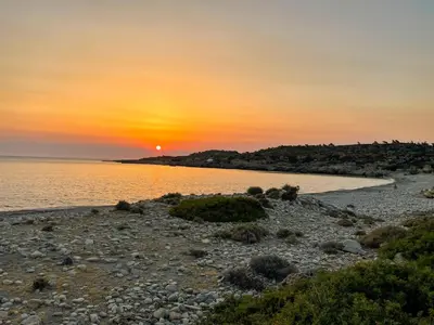 a sunset on a beach with the sun setting over the water at VILLA DEMETRA in Kissamos