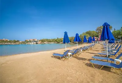 a row of chairs with blue umbrellas on a beach at Luxury Seaside Villa Plumeria ,50m to Sandy Beach, Chania in Tersanas