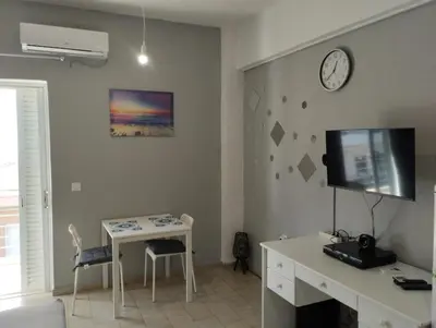 a living room with a desk and a clock on the wall at central cozy and lovely house in Chania Town