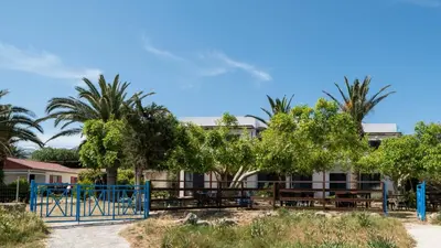 a building with palm trees and a playground at Milos Alexandra Studio in Frangokastello