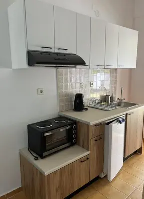 a kitchen with white cabinets and a stove top oven at Milos Alexandra Studio in Frangokastello
