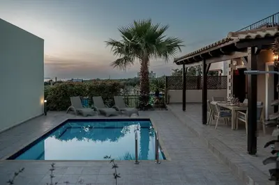 a swimming pool with chairs and a table on a patio at La Torre Villa in Palio Gerani