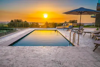 a swimming pool with an umbrella and a sunset at Falasarna's Dream in Kissamos
