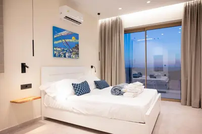 a bedroom with a white bed with blue pillows at Falasarna's Dream in Kissamos