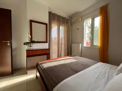 a bedroom with a bed and a mirror and a window at Seaside cozy apartment in Aghii Apostoli