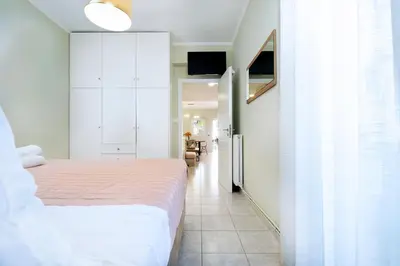 a white bedroom with a bed and a kitchen at Gigis Apartment in Chania Town