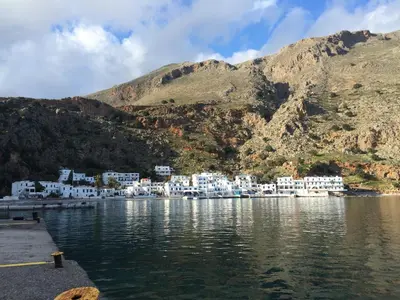 a group of white buildings on the shore of a body of water at Hotel Porto Loutro on the Hill in Loutro
