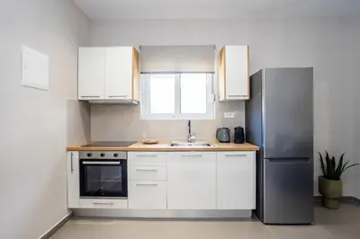 a kitchen with white cabinets and a stainless steel refrigerator at Fanouris Luxury Apartments in Chania Town