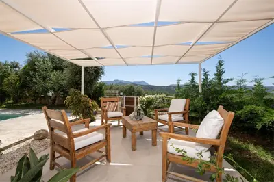 a white pergola with chairs and tables on a patio at Freya's Royal Estate, Kissamos in Khairethianá