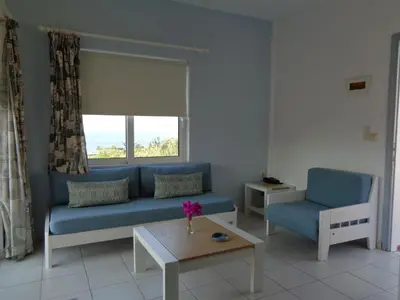 a living room with a blue couch and a table at Artemis Apartments in Kalyves
