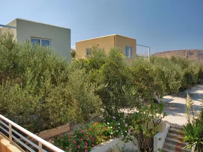 a house with a bunch of bushes and flowers at Artemis Apartments in Kalyves