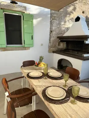 a wooden table with chairs and a fireplace at NiMa Maison in Kissamos