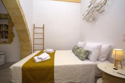 a bedroom with a bed with a yellow and white blanket at NiMa Maison in Kissamos