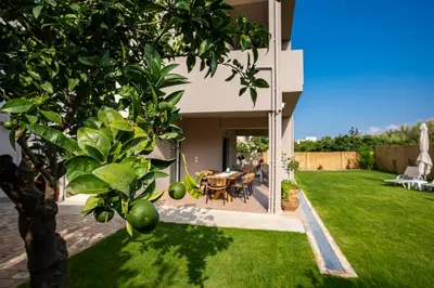 a house with a green yard with a table and chairs at Meraki Cretan Hospitality in Maleme