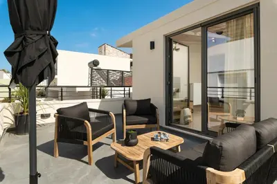 a patio with a couch and chairs on a balcony at Limani elegant apartments in Souda