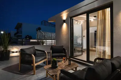 a living room with a couch and chairs on a patio at Limani elegant apartments in Souda