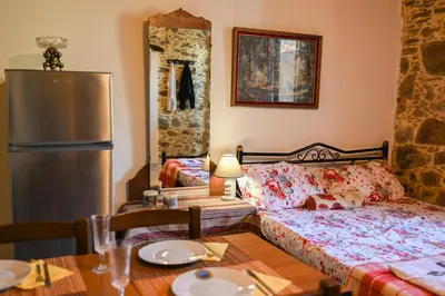 a bedroom with a bed and a table and a refrigerator at Stone house for relaxation in Elos in Kissamos