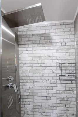 a shower in a bathroom with a brick wall at Casa Nicola's in Chania Town
