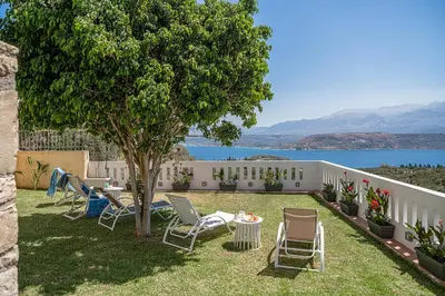 a yard with chairs and a tree and a fence at Elysian Sea-View Chania in Stérnai