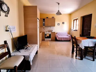 a living room with a table and a kitchen at Dreamy South Sea View Apartments with Pool in Frangokastello