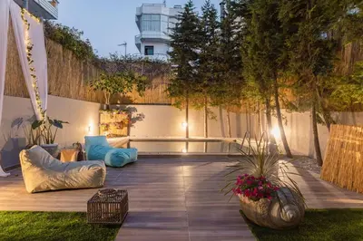 a patio with blue pillows and plants and a fence at G&M Luxury Residence with pool in Chania Town