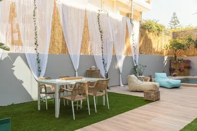 a patio with a white table and chairs on grass at G&M Luxury Residence with pool in Chania Town