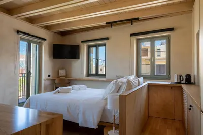 a bedroom with a bed with white sheets and windows at Kallergon Luxury Suites in Chania Town