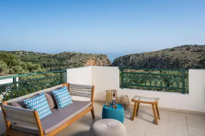 a patio with a couch and chairs and a view of the ocean at Villa Georgia Heated Pool & Jet-Tub in Kolymvari