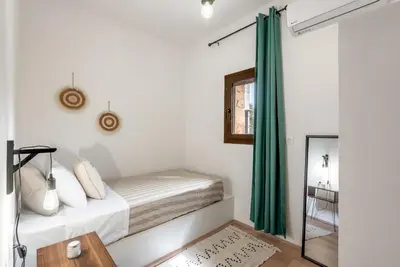 a bedroom with white walls and a bed with green curtains at Joel Living Collection - Rustic Villa in Áptera