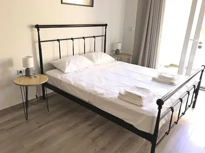 a bed with a black frame and white sheets and pillows at Pegasus Amazing Flat, 1,5min Walk To The Beach in Chania Town