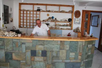 a man standing behind a stone counter in a store at Studios Stavris in Frangokastello