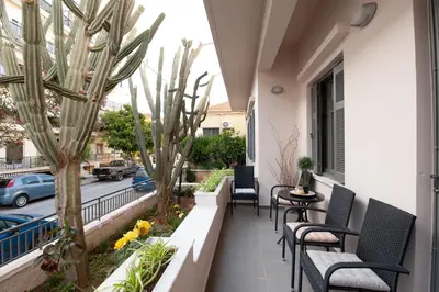 a balcony with chairs and tables and a palm tree at Cactus Residence Chania in Chania Town