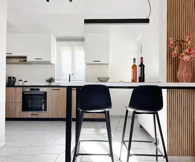 a kitchen with two black chairs at a counter at Anna's Apartment in Kato Daratso