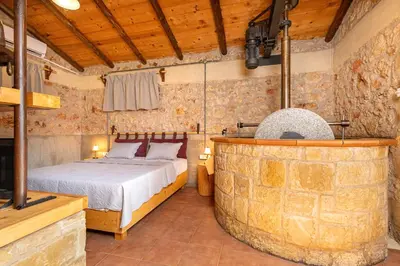 a bedroom with a bed and a large stone wall at Villa Fabrica Baladakis adults only in Metókhi