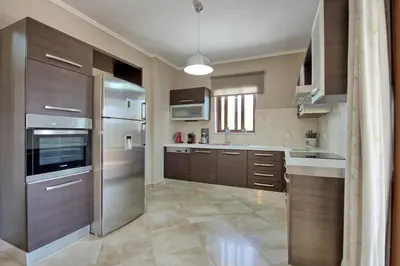 a kitchen with wooden cabinets and stainless steel appliances at Villa Kostantina by PosarelliVillas in Plaka