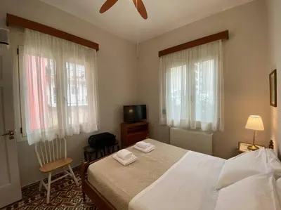a bedroom with a bed and a tv and two windows at Efi’s House in Chania Town