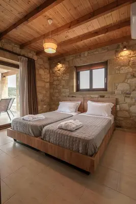 a bedroom with a large bed in a stone wall at Lithina charm villa with private pool and sea view in Kamisianá