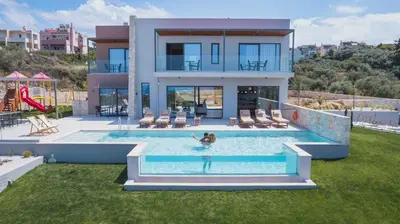 a person in a pool in front of a house at Star Luxury Villa - Private pool, gym, playground in Kato Daratso