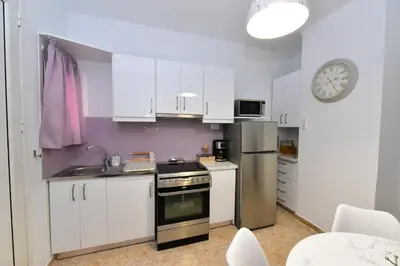 a kitchen with white cabinets and a stove and a clock at Zilina Homes2 in Chania Town