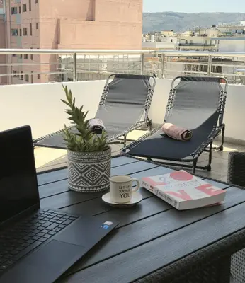a table with a laptop and a book on a balcony at Idene Penthouse in Chania Town