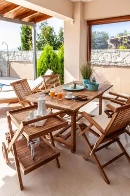 a wooden table and chairs on a patio at Vila Vasiliki, Next To Platanias, 6min From Sea in Vrísai