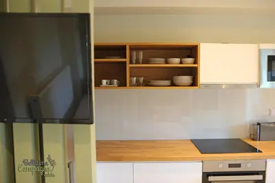 a kitchen with white cabinets and a flat screen tv at Bellisima Campagna Cabin Pelekapina - Chania Crete in Chania Town