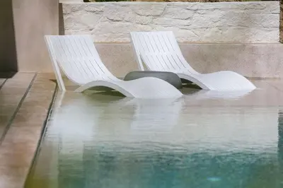 two white chairs sitting next to a pool of water at Heniochos Villas in Chania Town