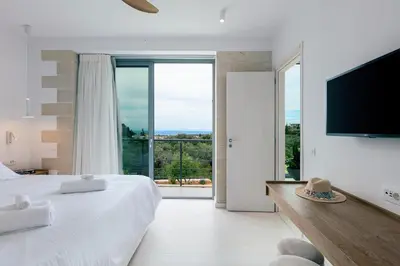 a bedroom with a large bed and a large window at Heniochos Villas in Chania Town