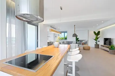 a kitchen with a wooden counter top and white chairs at Le Mont Blanc - with shared Pool in Kounoupidhianá