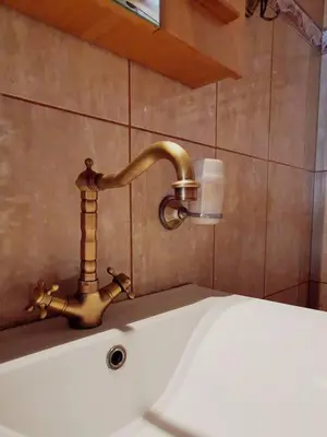 a bathroom sink with a brass faucet on a wall at Sweet Home Leo in Chania Town