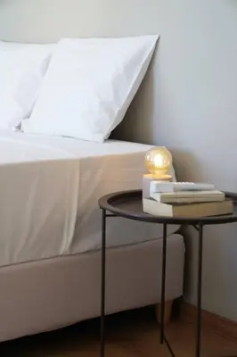 a bed with a side table with books and a lamp at Venetian Owl, 1min To Lighthouse in Chania Town
